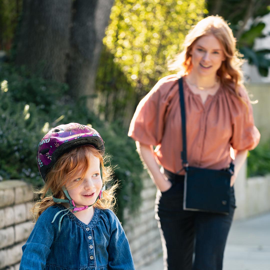 Parent on a walk with toddler carrying The Crossbody Kit