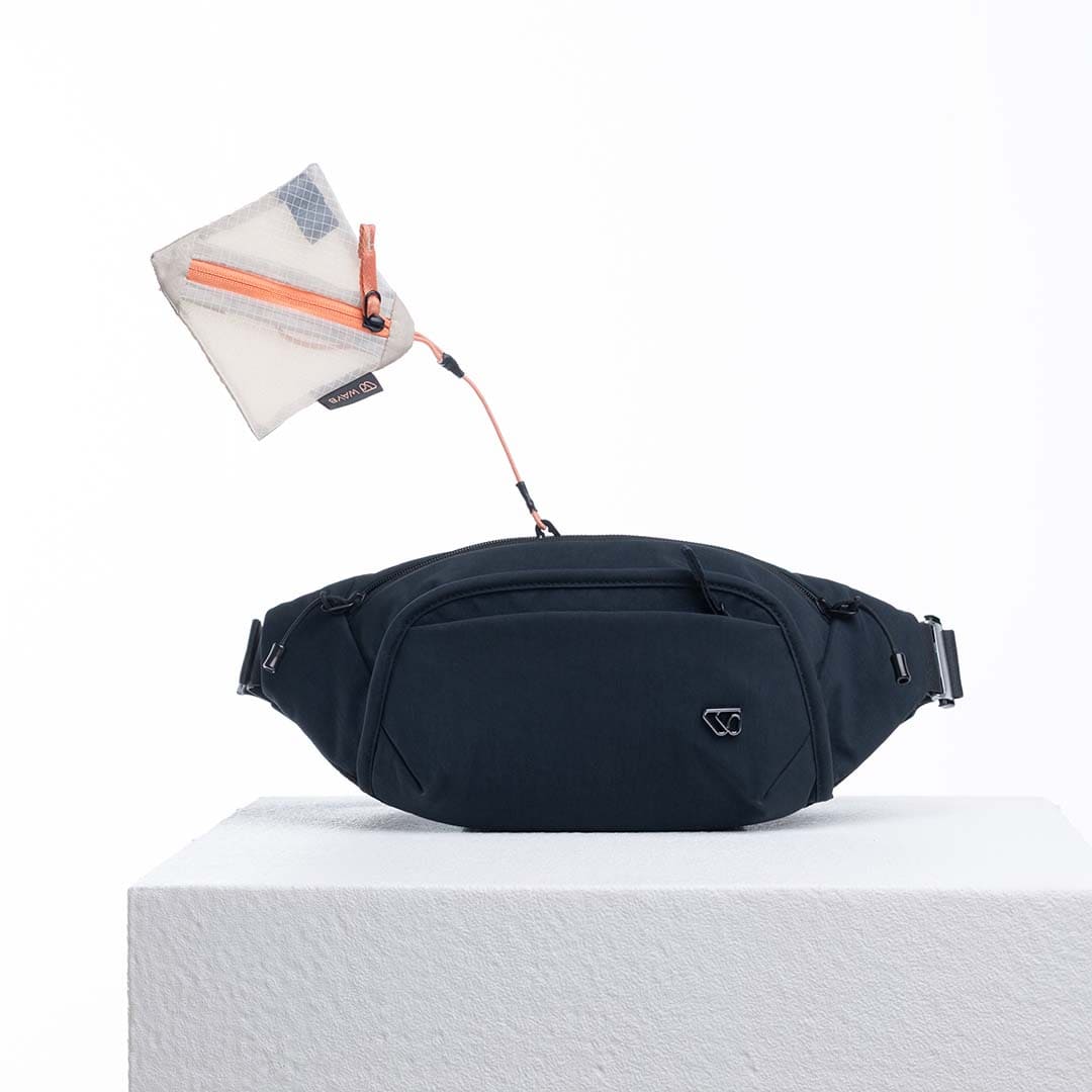 Black waist bag with a small white pouch on a light gray background