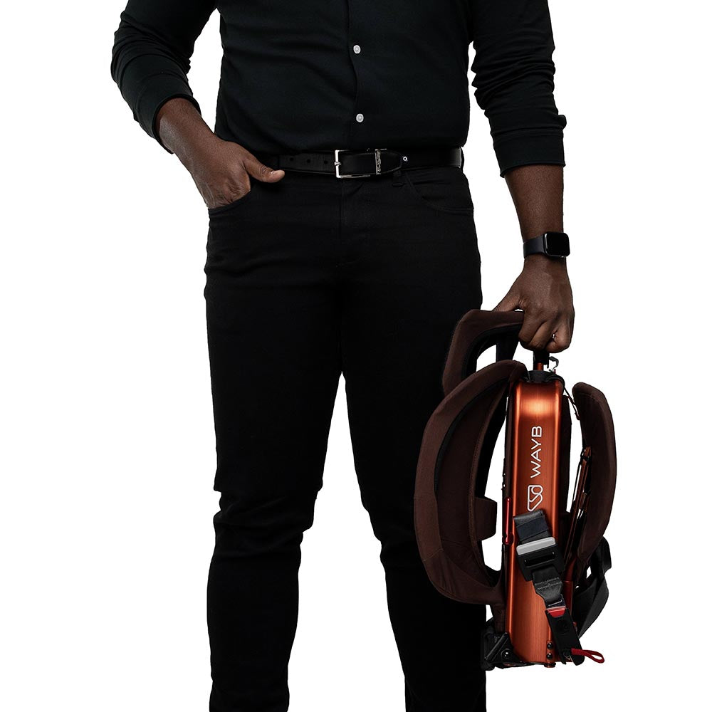 Parent carrying collapsed WAYB Pico Car Seat in color: Golden Hour