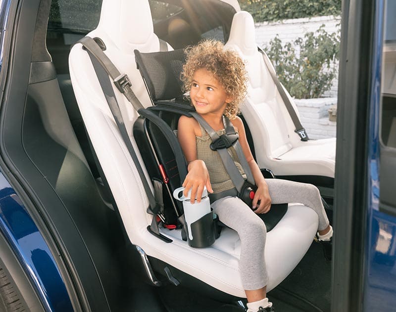 Child in a car seat inside a vehicle with a cup.