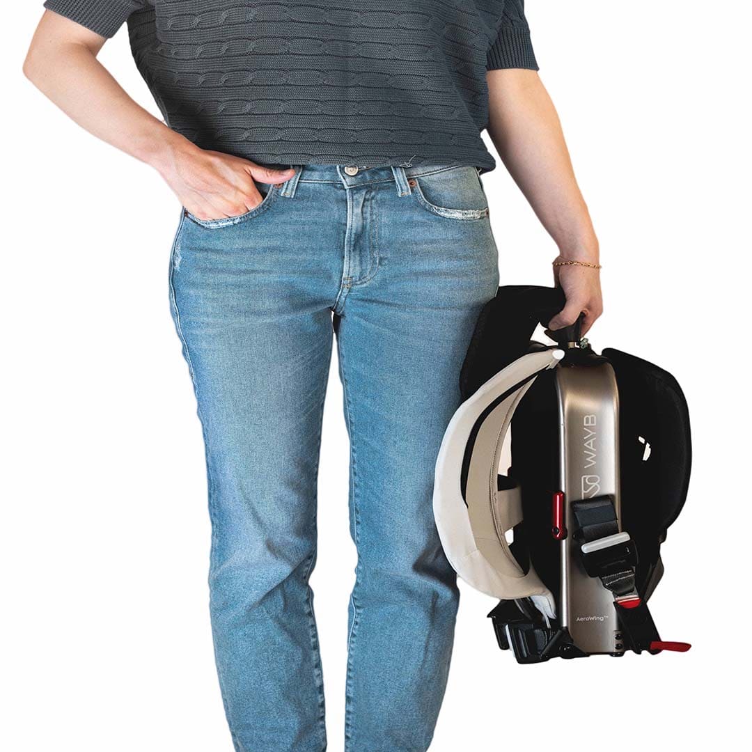 Person wearing blue jeans holding a black and white carseat with visible branding.