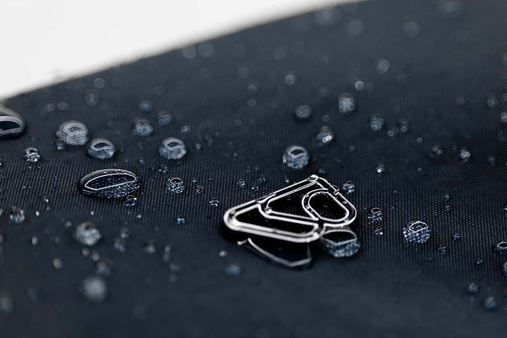 Silver earring on a black fabric surface with water droplets