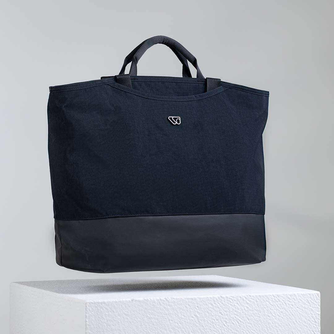 Black tote bag with a logo on a light gray background